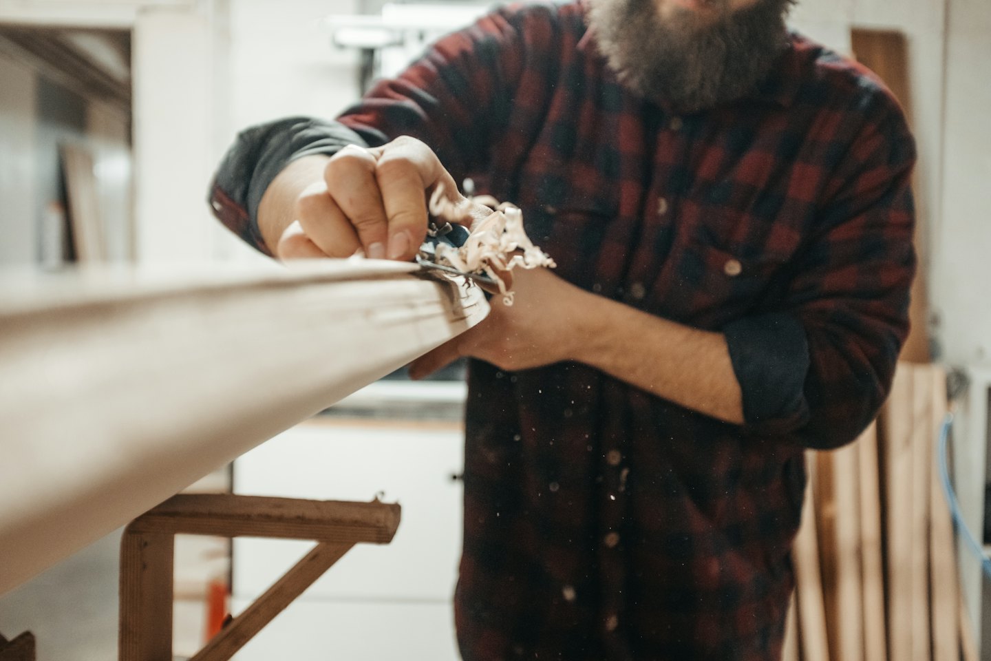 Un falegname usa una pialla per modellare una tavola di legno.